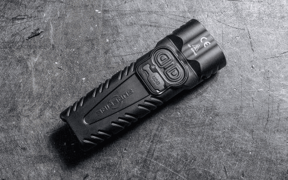 Compact black flashlight photographed on a scratched metal surface