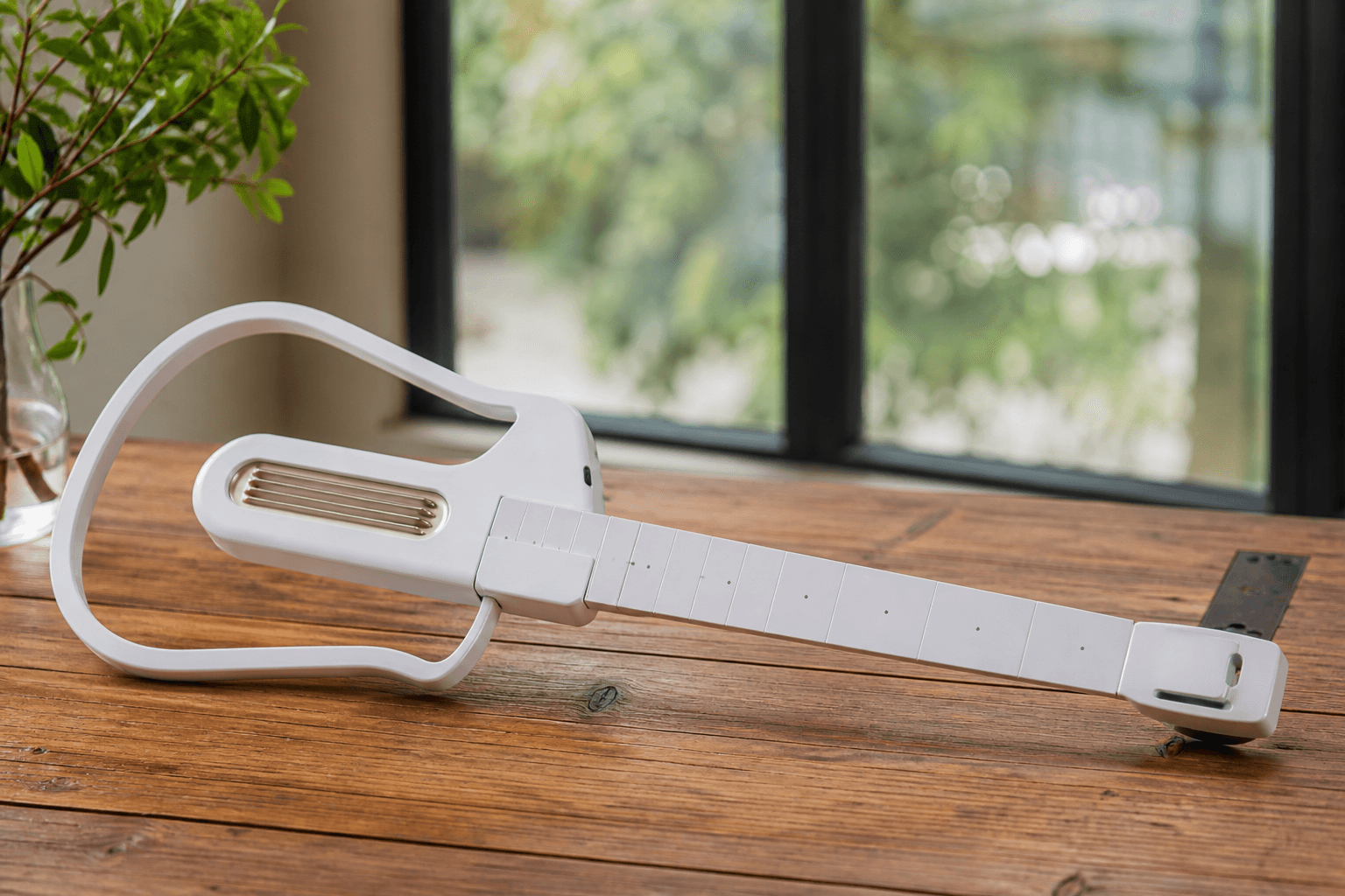 LiberLive C1 stringless smart guitar on a wooden table in soft daylight