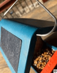 Birdbuddy Pro side view showing the solar roof, handle, and seed tray