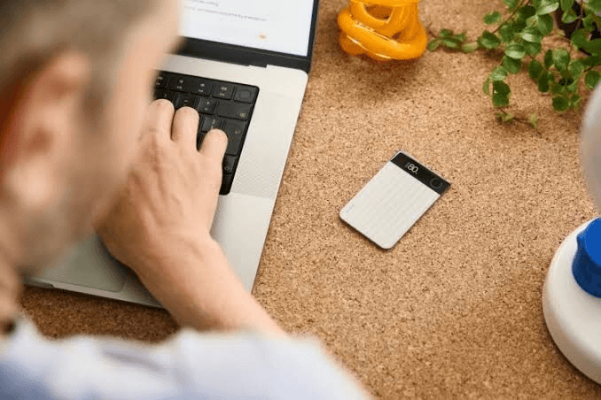 PLAUD Note Pro on a cork desk beside a laptop during a work session