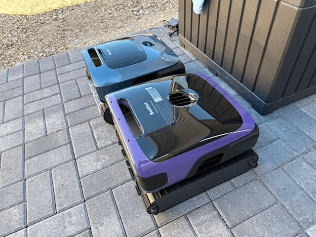 Two Beatbot Sora 70 pool cleaners on a patio beside pool equipment